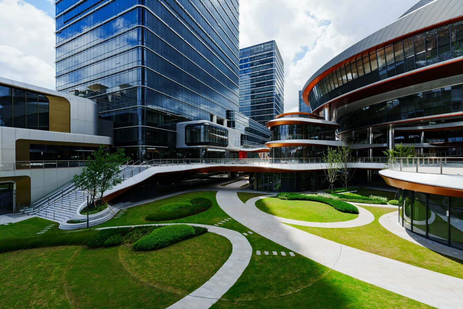 Glass office buildings around a landscaped courtyard with lawns, curving paths and young trees